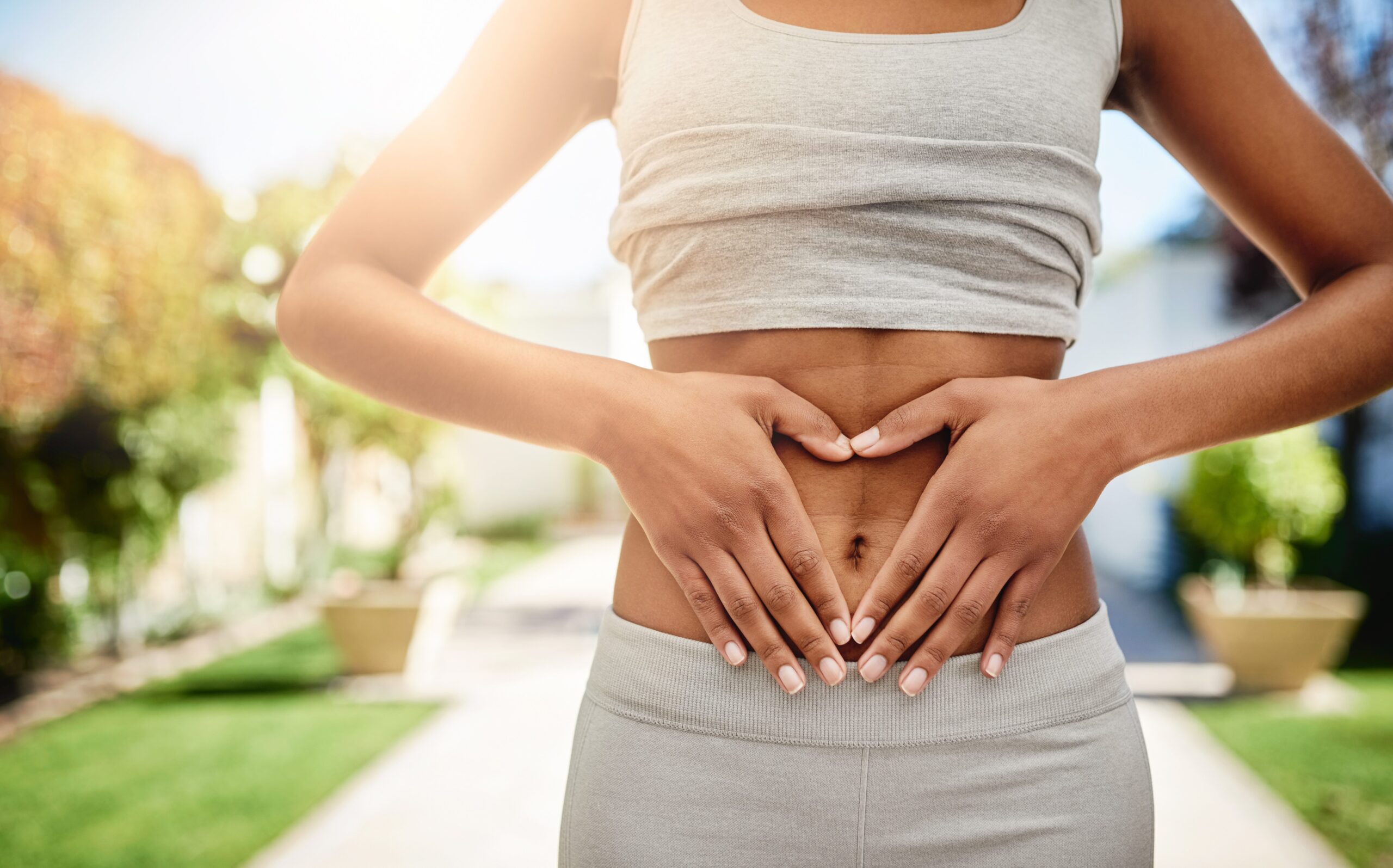 Frau legt beide Hände auf ihren Bauch – Symbolbild für Darmgesundheit und Verdauungsbeschwerden